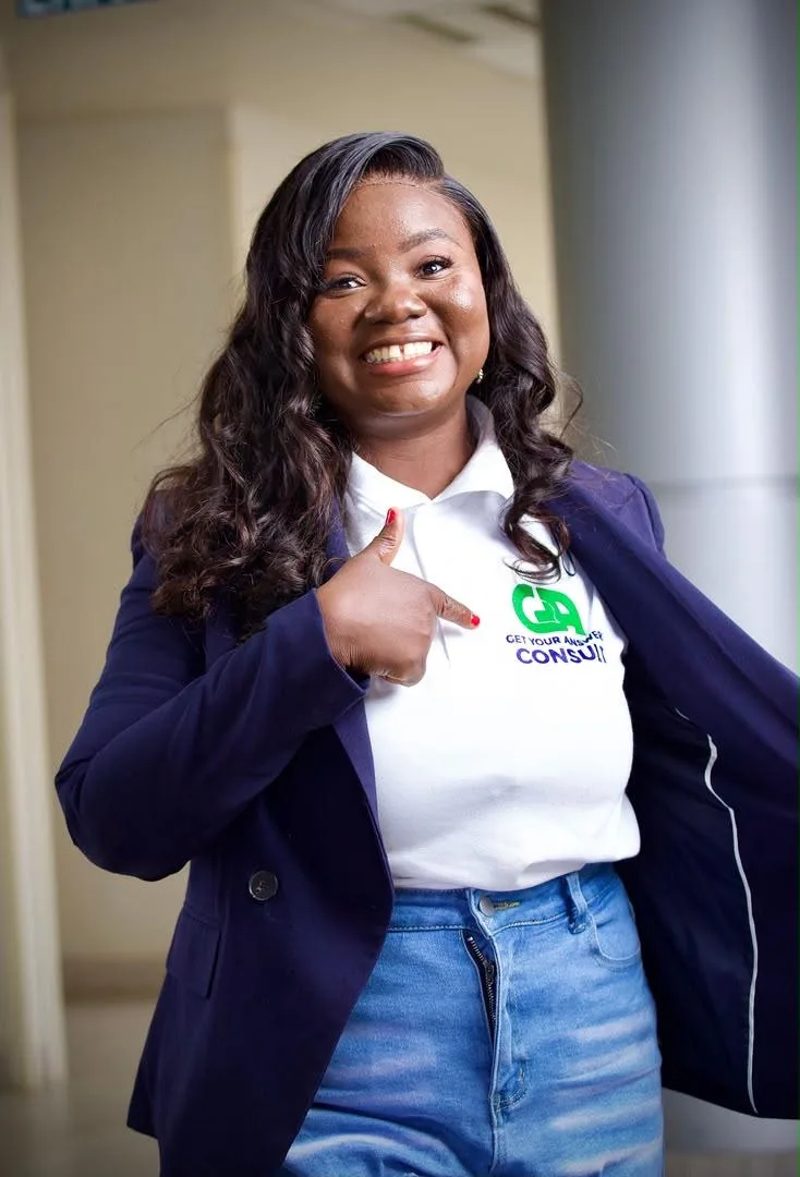 A woman wearing a jacket and a white shirt with a green logo on it.
