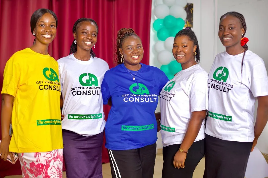 Five women wearing blue and white shirts that say "Get Your Answers Consult" pose for a picture.